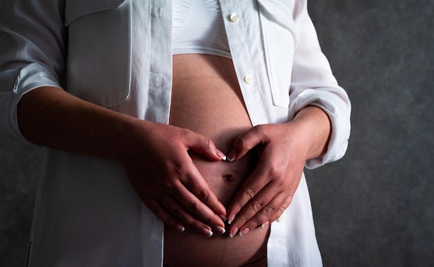El vientre de una mujer embarazada concepto de embarazo mujer con las manos en forma de corazón