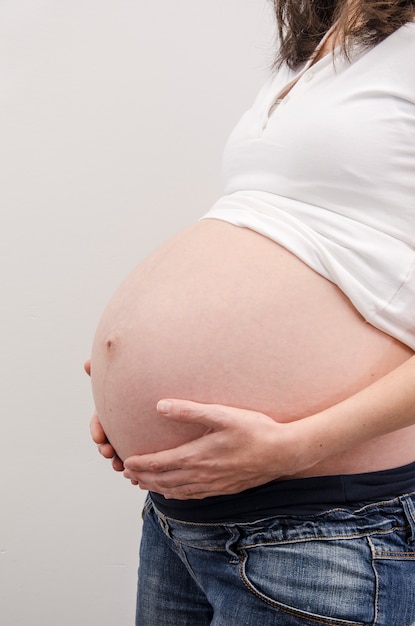 Vientre de mujer embarazada con manos.