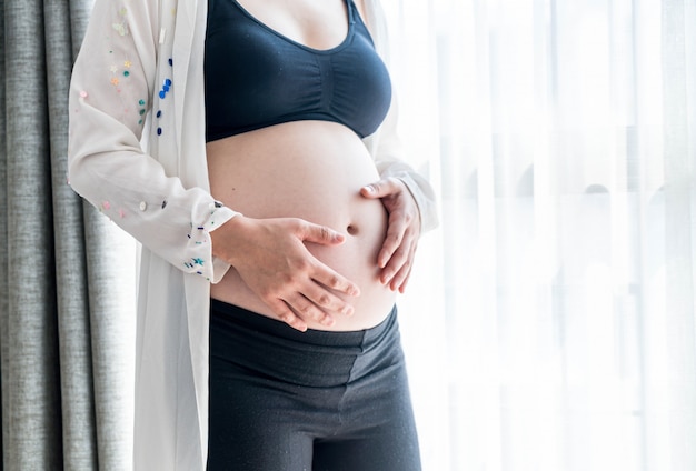 Vientre de mujer embarazada con manos.