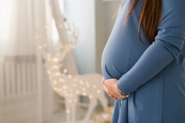 Vientre de una mujer embarazada con un vestido azul