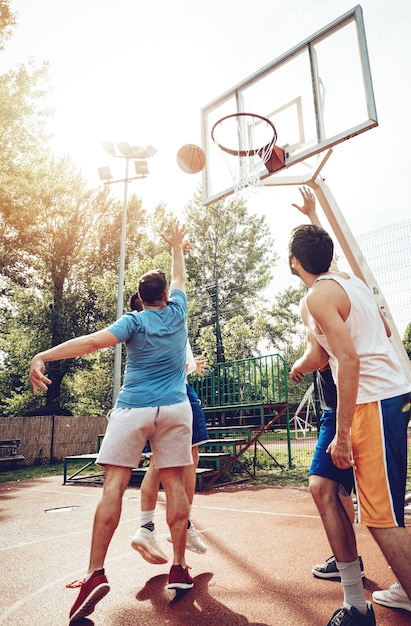 Vier Basketballspieler haben ein Training im Freien. Sie spielen und machen gemeinsam Aktionen.