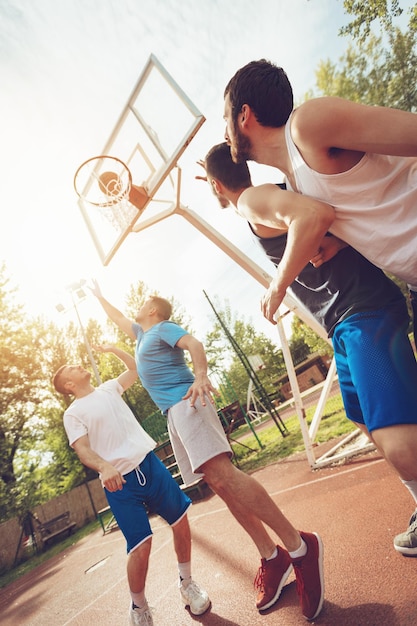 Vier Basketballspieler haben ein Training im Freien. Sie spielen und machen gemeinsam Aktionen.