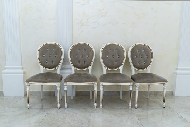 Vier braune antike Stühle stehen in einer Reihe.