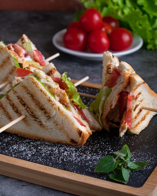 Foto vier club-sandwiches mit salatkirschtomaten und käse auf dem brett vertikal