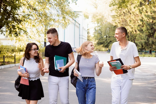 Vier Freunde mit Büchern und Papieren gehen nach den Vorlesungen nach Hause