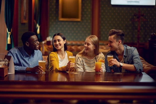 Vier fröhliche Freunde trinken Alkohol an der Theke in der Bar