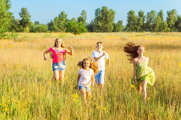 Foto vier glückliche schöne kinder, die am schönen sommertag zusammen spielen und spielen. springen und blick in die kamera mit glück und zahnigem lächeln.