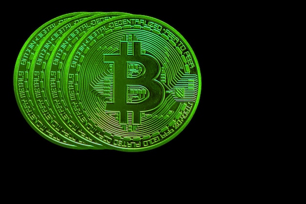 Vier grüne Bitcoins aus Kryptowährung während des steigenden Marktes auf schwarzem Hintergrund