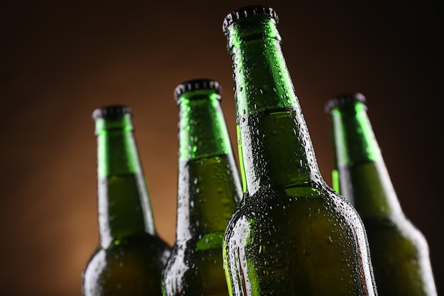 Vier grüne Glasflaschen Bier auf dunkel beleuchtetem Hintergrund, Nahaufnahme