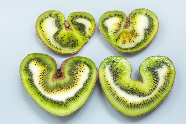 Vier Hälften einer herzförmigen hässlichen Kiwi in einem Abschnitt auf grauem Hintergrund.