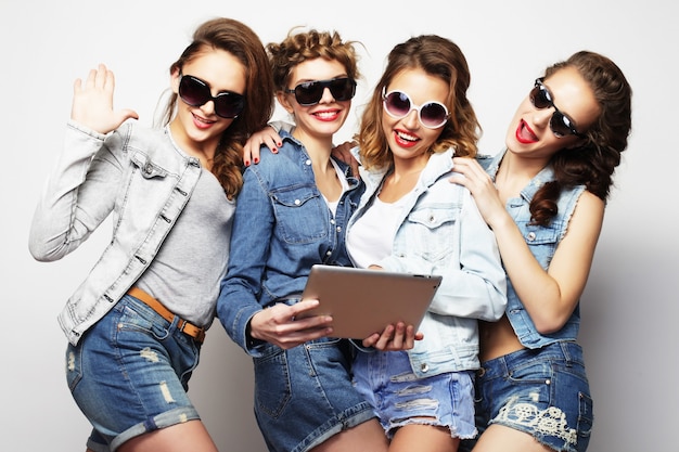 Vier Hipster-Freundinnen benutzen ein digitales Tablet