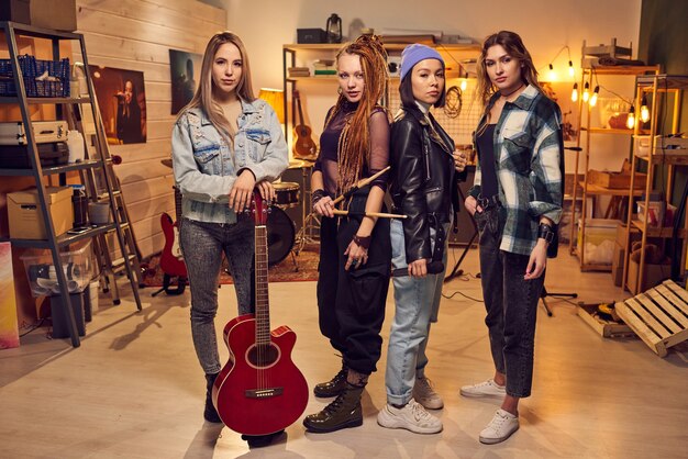 Vier junge Frauen in Freizeitkleidung stehen in einem großen modernen Tonstudio