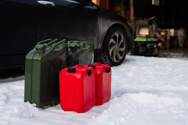 Vier Kanister mit Benzin stehen im Schnee gegen Auto