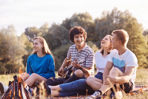 Vier kaukasische Freundinnen und Freunde lachen freudig zusammen