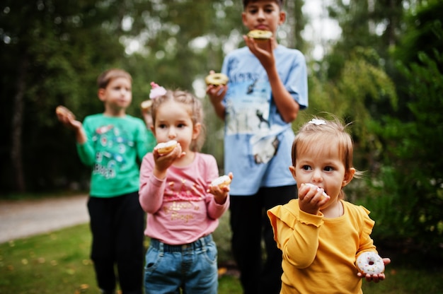 Vier Kinder mit Donuts am Abendhof. Leckeres leckeres Donut-Essen.