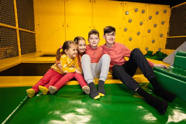 Vier Kinder sitzen zusammen auf dem Spielplatz, Schwestern und Brüder bei aktiver Unterhaltung