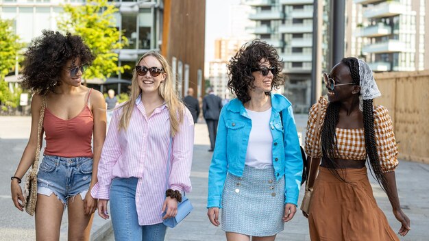 Foto vier mädchen, teenager der generation z in der stadt, junge frauen, die spaß beim spazierengehen in der stadt haben