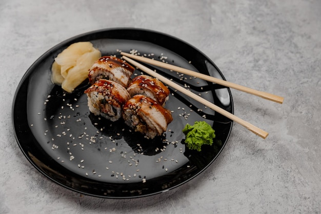 Foto vier portionen garnelen- und aal-sushi mit vossabi-sauce und ingwer auf einem schwarzen teller.seitenansicht