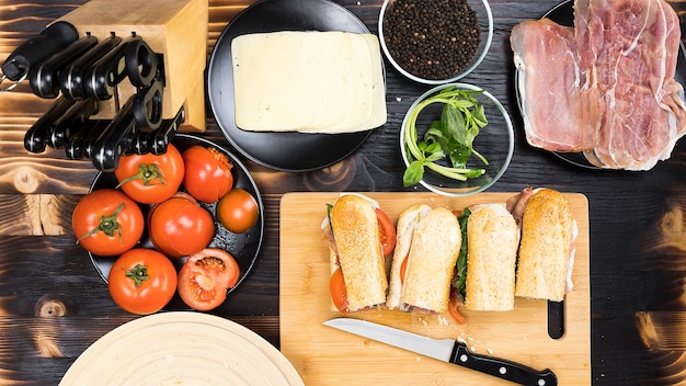 Vier Sandwiches auf dem Küchentisch, umgeben von den Zutaten, aus denen sie bestehen