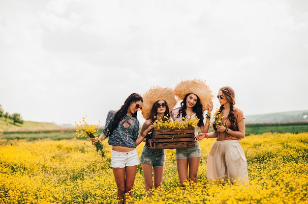 vier schöne Hippie-Mädchen in einem Feld von gelben Blumen