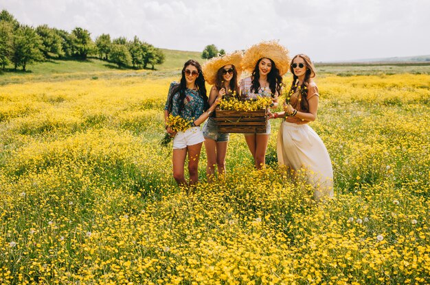 Foto vier schöne hippie-mädchen in einem feld von gelben blumen