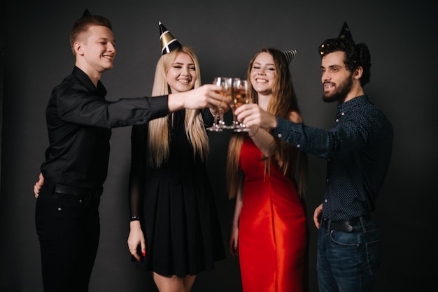 Vier schöne und fröhliche Freunde in festlicher Kleidung, die mit Champagner anstoßen