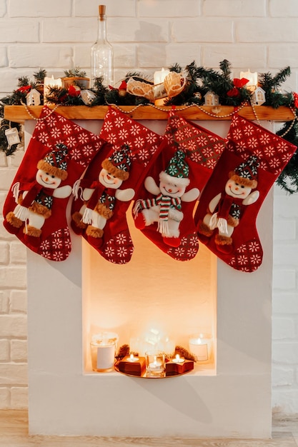 Vier weihnachtliche rote Socken hängen am weißen Kamin im Zimmer
