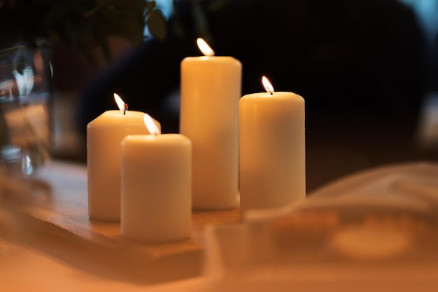 Vier weiße Kerzen mit brennendem Docht auf einem Tisch