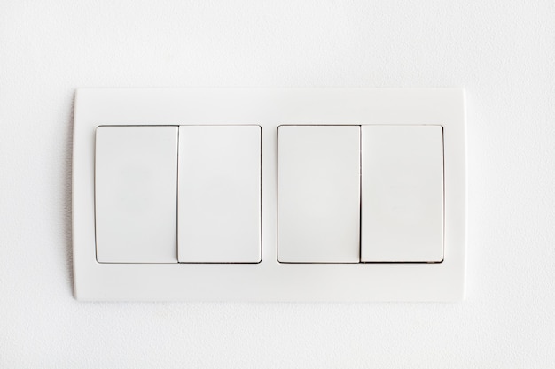 Vier weiße Lichtschalter an einer weißen Wand in einer Nahaufnahme
