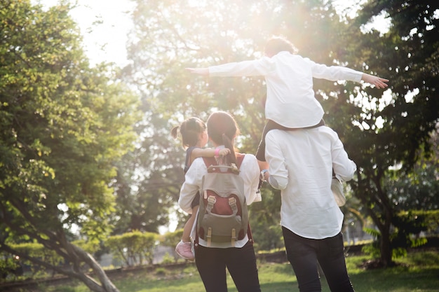 Vierköpfige Familie, die auf grasartige, Vater geben Tochter auf Hals in den Park geht.