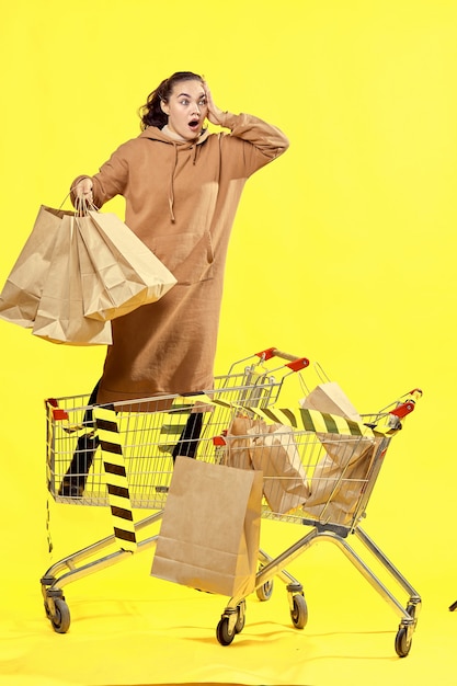 Foto viernes negro. una niña con bolsas con una expresión de sorpresa en su rostro, de pie en una canasta de compras.
