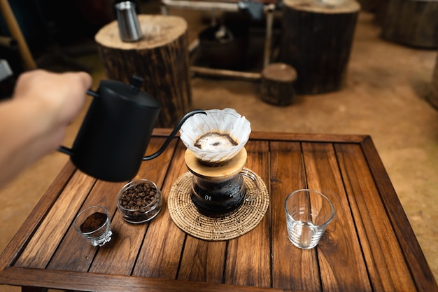Vierta agua caliente en el café., Gotee el café sobre una mesa de madera en casa