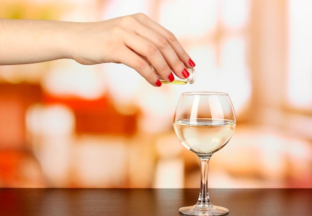 Vierta algo en un vaso con una bebida en una mesa de madera en el fondo de la habitación