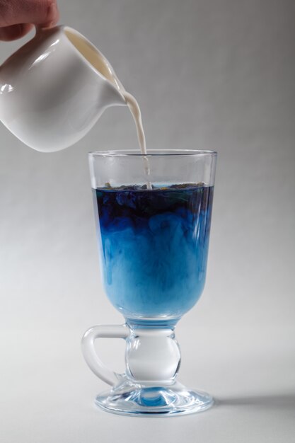 Foto vierta la leche en una taza de té de arveja azul, té anchan. té azul tailandés y leche mezclada