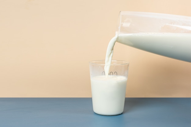 Foto vierta la leche en un vaso de una botella de leche de vidrio grande.