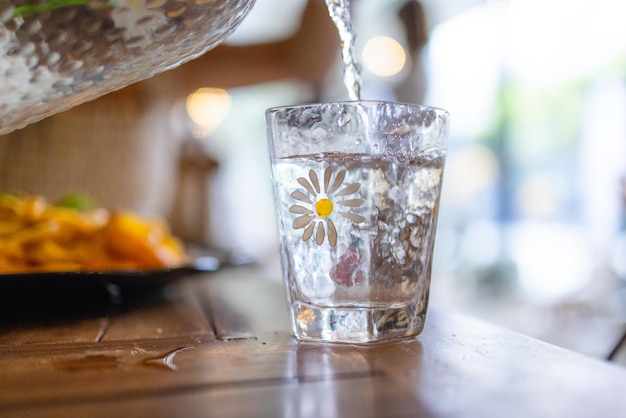 Vierte agua en el vaso en la mesa.