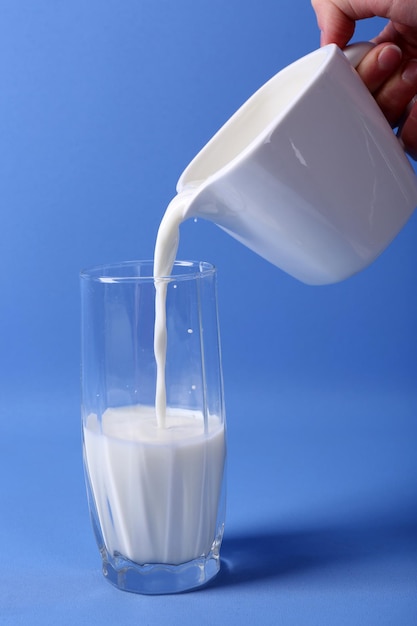 Vierte leche en vaso sobre fondo azul.
