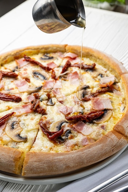 Se vierte una pizza con champiñones y jamón en un plato blanco.