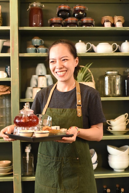 Vietnamesische junge Frau serviert Tee in einem Café