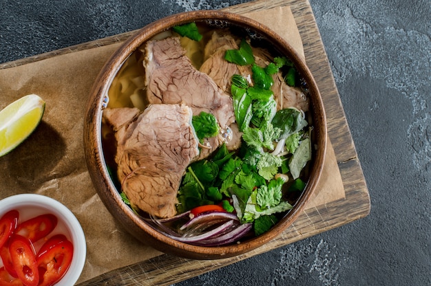 Vietnamesische Pho Bo Suppe in einer Holzschale auf dunklem Hintergrund