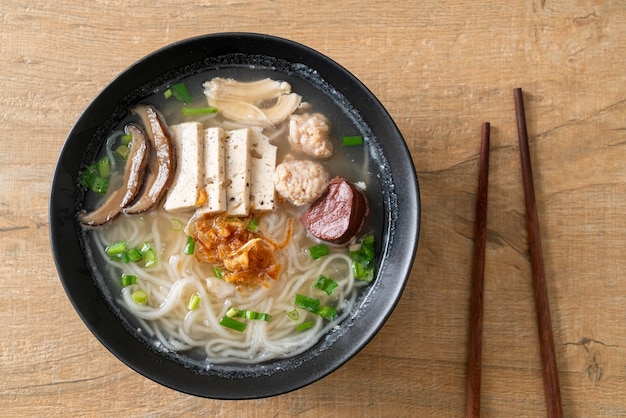 Vietnamesische Reisnudelsuppe mit vietnamesischer Wurst, serviert mit Gemüse und knusprigen Zwiebeln - asiatisches Essen