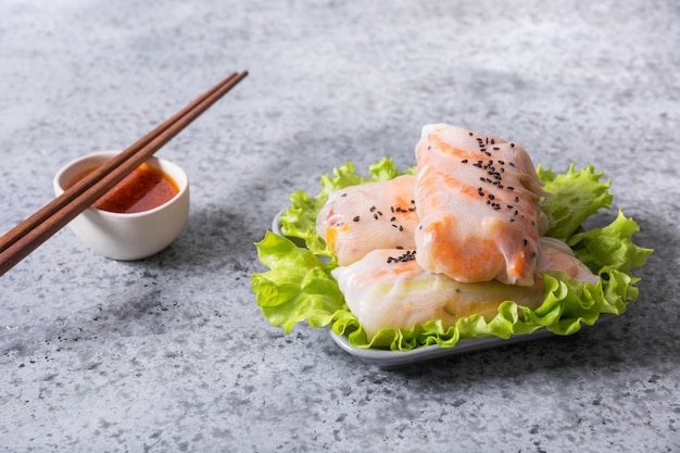 Vietnamesisches Essen Frühlingsrollen mit Gemüse, Garnelen in Reispapier auf grauem Steinhintergrund. Vertikales Format. Asiatische Küche.