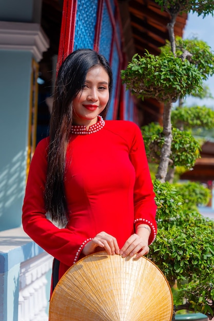 Foto vietnamesisches mädchen mit ao dai-kleidung steht in einem traditionellen haus vietnams text auf dem foto bedeutet beste wünsche für familienglück, wohlstand, gesundheit, tet-ferien und neujahr