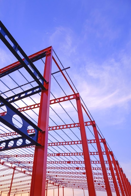 Viga almenada roja y negra de estructura de edificio industrial en sitio de construcción al atardecer