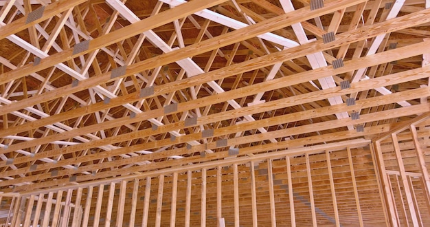 Las vigas del techo de un nuevo edificio residencial en construcción se ven en la viga del poste del techo fra