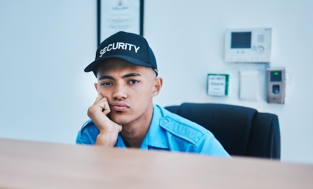 Vigilância de retratos e um guarda de segurança entediado sentado em uma mesa em seu escritório para servir e proteger a segurança e o controle do CCTV com um policial cansado trabalhando como funcionário de serviço privado