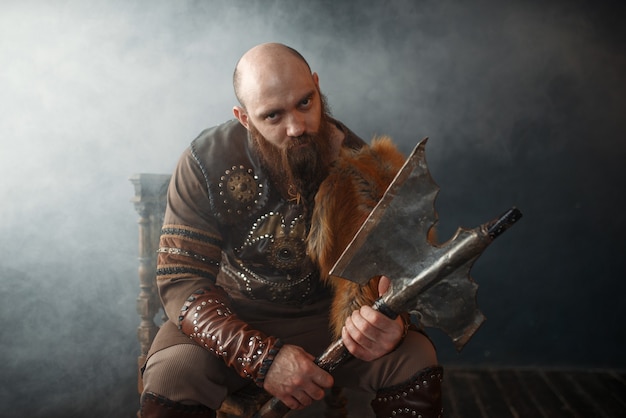 Viking barbudo com machado sentado na cadeira