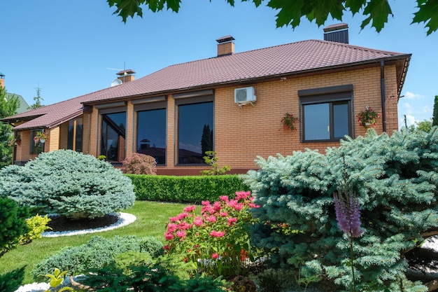 Villa de estilo europeo con jardín con arbustos muy bien cuidados en frente de la casa. Diseño de exteriores. Foto de alta calidad