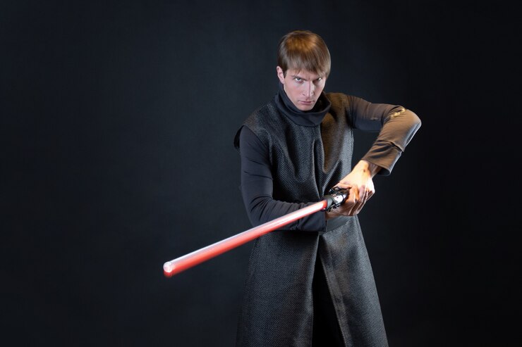 Foto un villano con un sable de luz rojo un joven con una túnica larga hace poses de lucha