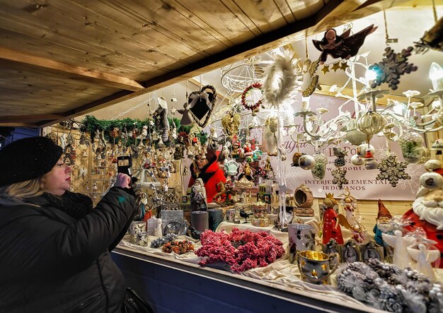 Vilna, Lituania - 4 de diciembre de 2016: Mujer que elige la decoración de Navidad en el mostrador del mercado navideño en la Plaza de la Catedral en el casco antiguo, Vilna, Lituania.